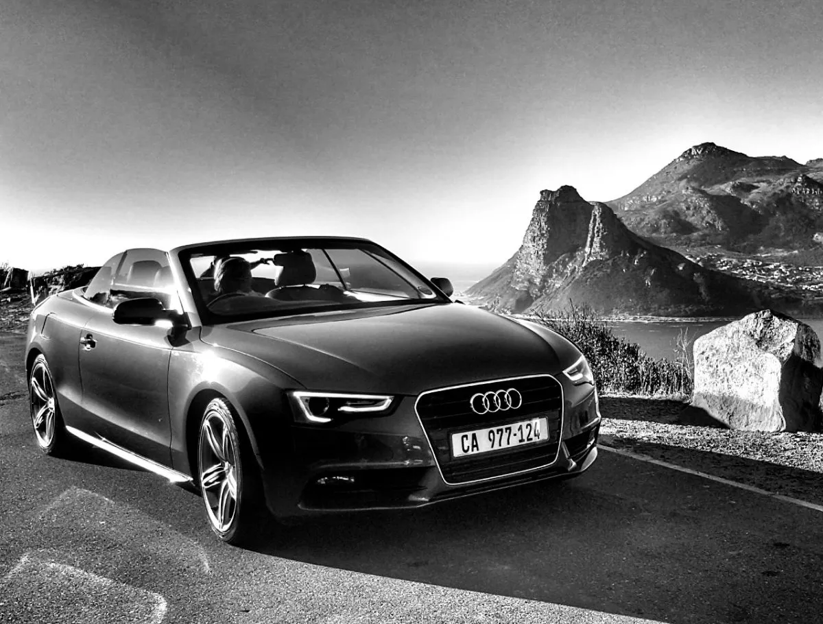 A black convertible parked on a coastal mountain road